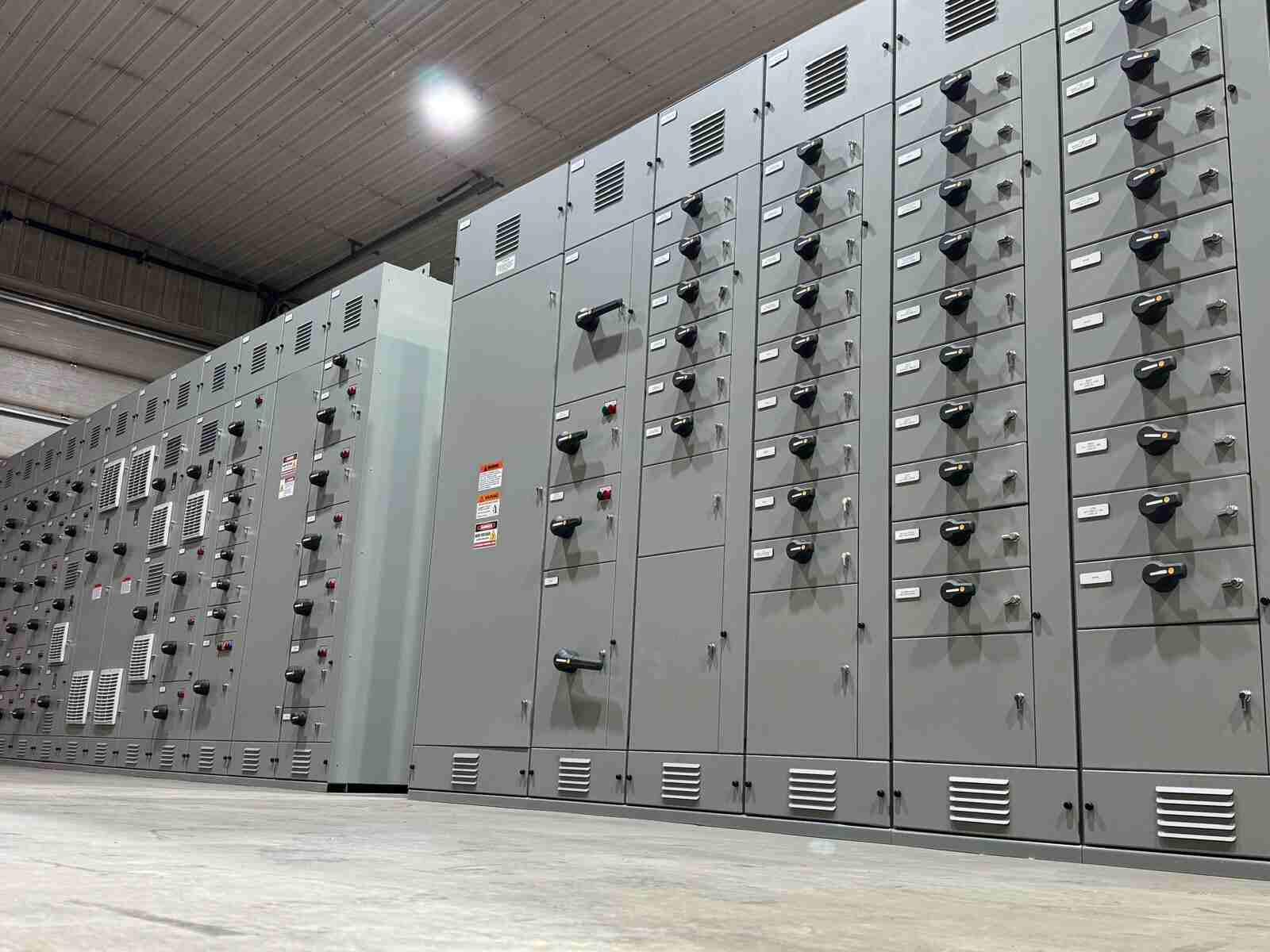 Hydroelectric Rows of industrial control panels featuring switches, vents, and indicator lights, representing control panels across different energy sources in a modern facility.